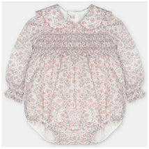 Baby girl romper in woven fabric with smocking, featuring a floral pattern in pink and blue, long sleeves, and a Peter Pan collar.