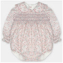 Baby girl romper in woven fabric with smocking, featuring a floral pattern in pink and blue, long sleeves, and a Peter Pan collar.