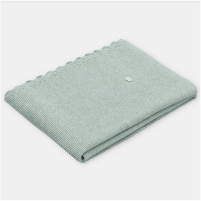 Sweater knit cotton blend blanket in Pravia sage color, featuring a scalloped edge and a small decorative tag.