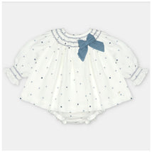 Woven fabric baby dress and bloomer set in white with navy polka dots and a blue bow on the collar.