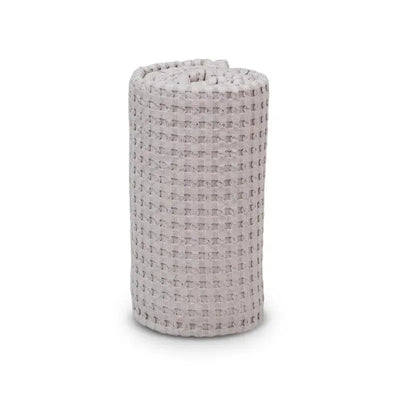 Waffle blanket in sand color, rolled up, showcasing textured fabric, ideal for comfort and warmth.