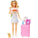 Barbie doll in a casual outfit holding a camera, with a pink suitcase, travel accessories, and a puppy by her feet.