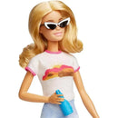 Barbie doll wearing sunglasses and a colorful shirt, holding a blue spray bottle, styled for a Malibu summer theme.