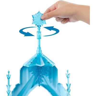 A hand is turning a snowflake-shaped top on the Mattel Disney Frozen Elsa Ice Castle playset, showcasing its blue structure.