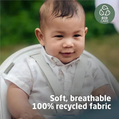 Baby seated in a highchair with soft, breathable fabric, smiling with a nature background. Text highlights eco-friendly materials.