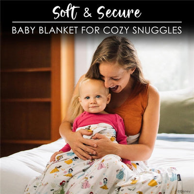 Soft Disney Princess swaddle blanket wrapped around a toddler, who sits on a bed with a smiling mother.