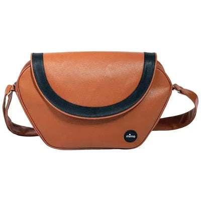 Trendy camel changing bag by Mima featuring a sleek design with a dark blue curved flap and an adjustable strap.