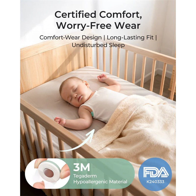 Smart baby thermometer attached to a sleeping infant in a crib, featuring comfort-wear design and hypoallergenic material.