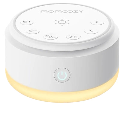 White Momcozy white noise machine with control buttons and a soft amber light at the base.