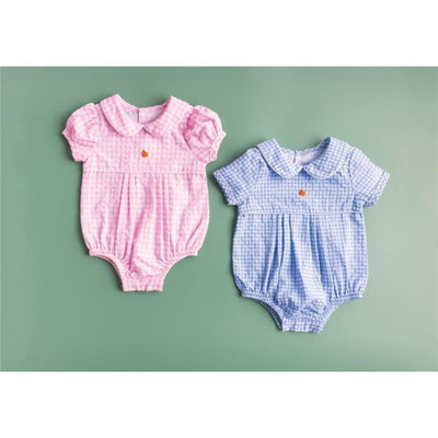 Baby pink and blue gingham bubble rompers with short puff sleeves and front button detail, displayed on a green background.