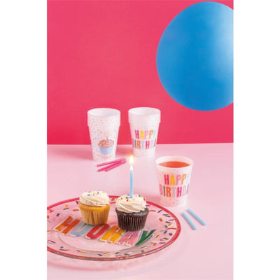Happy Birthday Party Cup Set featuring colorful cups, cupcakes with frosting and a candle, and a blue balloon on a pink background.