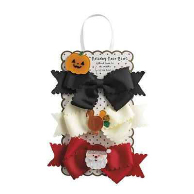 Set of three holiday hair bows: black, white with a turkey, and red with a Santa face, displayed on a decorative card.