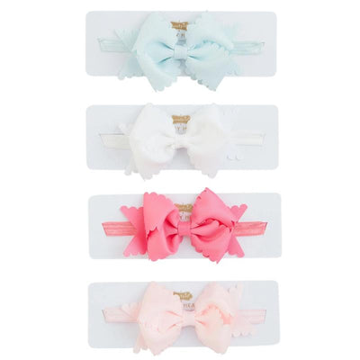 Four scalloped bow headbands in blue, white, pink, and light pink, displayed on a white card with brand label.