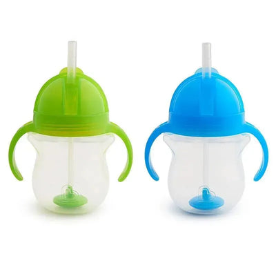 Munchkin Any Angle Straw Trainer cups in green and blue, featuring easy-grip handles and flexible straws.