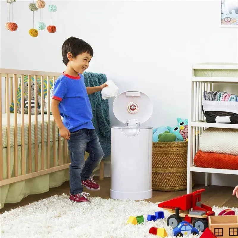 Child holding a diaper while smiling next to a Munchkin Arm & Hammer Diaper Pail in a colorful nursery.