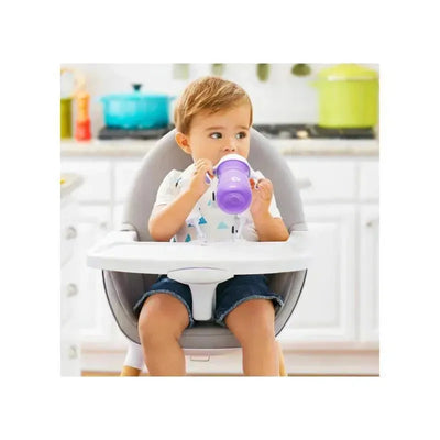 Child in a high chair sipping from a purple Munchkin 10oz sippy cup, wearing a playful patterned shirt.
