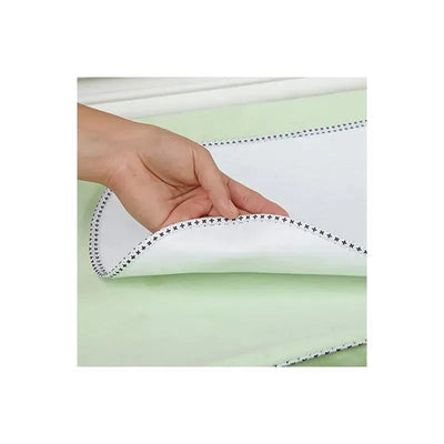Munchkin Waterproof Changing Pad Liner, showing a hand lifting the white liner with black star stitching over a green surface.