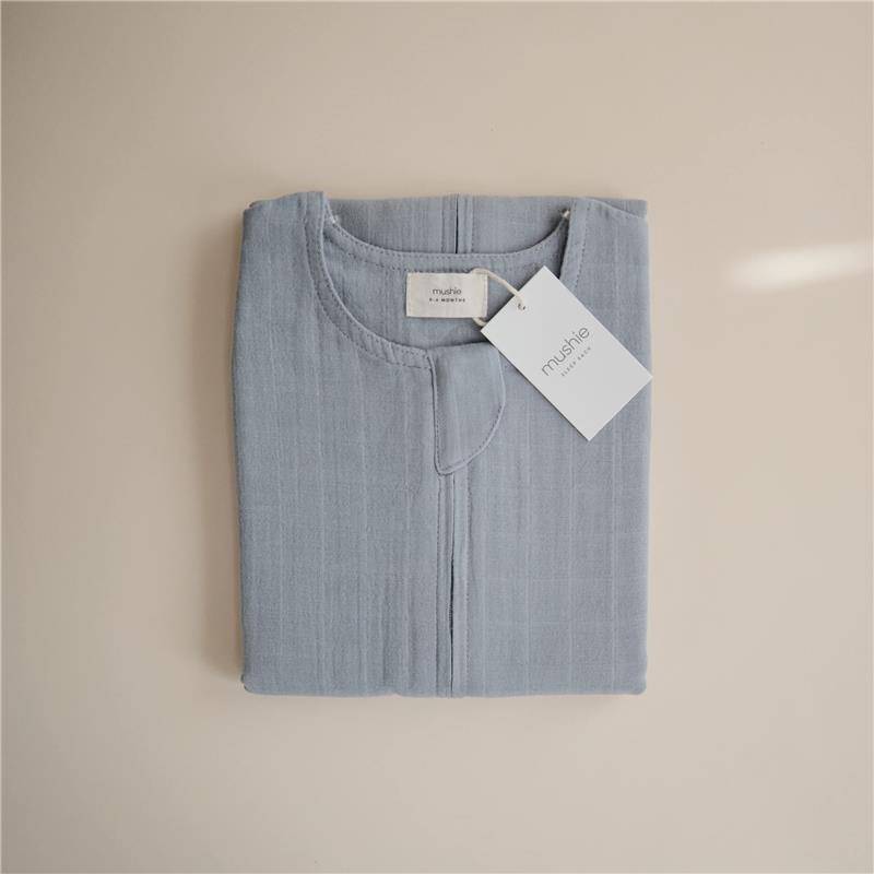 100% organic cotton muslin baby wearable blanket in Tradewinds color, folded with a tag showing the brand Mushie.