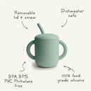Silicone training cup in soft green with removable lid and straw, labeled as BPA-free and dishwasher safe.