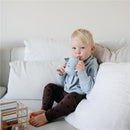 Toddler with blonde hair, wearing a light blue sweatshirt, sipping from a blue silicone training cup with planet designs.
