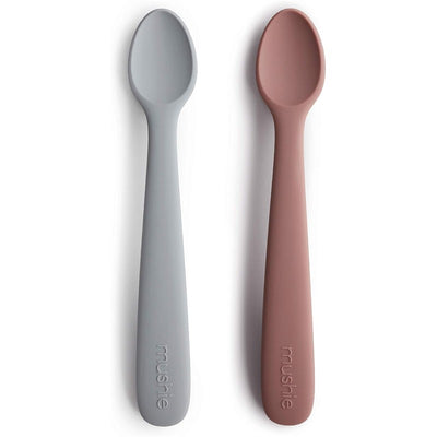 Silicone feeding spoons by Mushie in stone and cloudy mauve colors, designed for feeding infants.