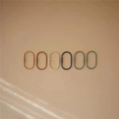 Mushie Chain Link Rings in natural, stone, and Tradewinds colors displayed on a light background.