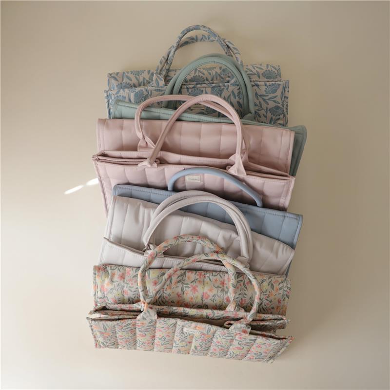 Mushie Baby Diaper Caddy in pastel colors, featuring organized compartments and floral patterns for newborn essentials.