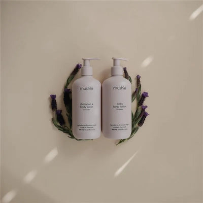 Mushie lavender baby shampoo and body wash beside baby body lotion, both 400 ml, surrounded by lavender sprigs.