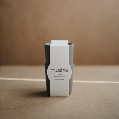 Mushie silicone cups set in smoke color, featuring a minimalistic label indicating dishwasher-safe use.