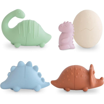 Mushie Dino Mold Free Bath Play Set includes four colorful dinosaur toys: a green brontosaurus, pink dino, blue stegosaurus, and brown triceratops, plus an egg.