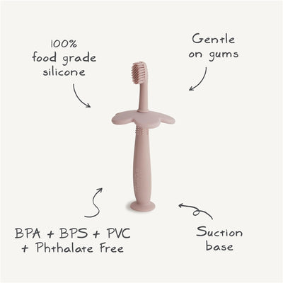 Mushie Silicone Flower Training Toothbrush in blush, made from 100% food-grade silicone, with gentle bristles and suction base.
