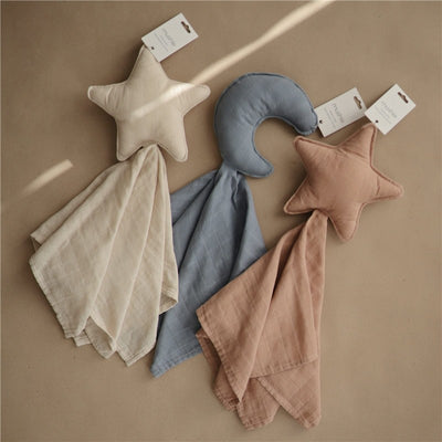 Mushie Moon Lovey - Tradewinds features three soft security blankets with plush star and moon designs in neutral colors.