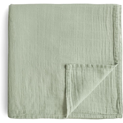 Mushie Organic Cotton Muslin Swaddle Blanket in sage green, featuring a soft, textured fabric with neatly sewn edges.