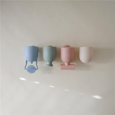 Mushie Silicone Pour and Play Bath Set featuring four colorful silicone cups in blue, green, pink, and neutral tones.