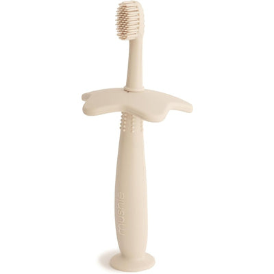 Mushie Silicone Star Training Toothbrush in Shifting Sand color, featuring a soft brush head and ergonomic star-shaped handle.