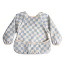 Water-resistant baby bib in blue check pattern with long sleeves and an adjustable fit, featuring a pocket.