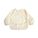 Water-resistant long sleeve baby bib featuring a soft cream background with pink bows, designed for adjustable fit.
