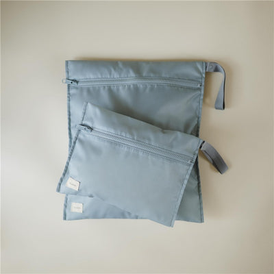 Two water-resistant wet bags in a soft blue color, one larger and one smaller, both with zippers and hanging loops.