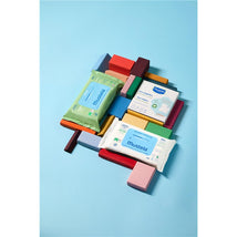 Mustela Compostable Cleansing Water Wipes package surrounded by colorful wooden blocks on a light blue background.