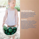 Mustela No-Rinse Cleansing Water bottle with a young child holding a basket of avocados, surrounded by nature.