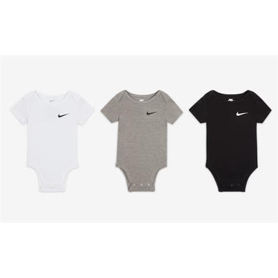 Three Nike bodysuits for newborns in white, gray, and black, each featuring a small black Nike logo on the chest.