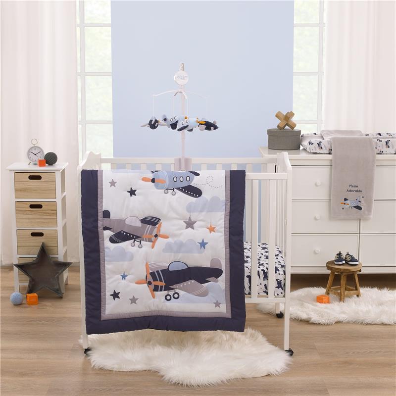 Mini crib bedding set featuring airplane designs, a matching mobile, and decorative items in a nursery setting.
