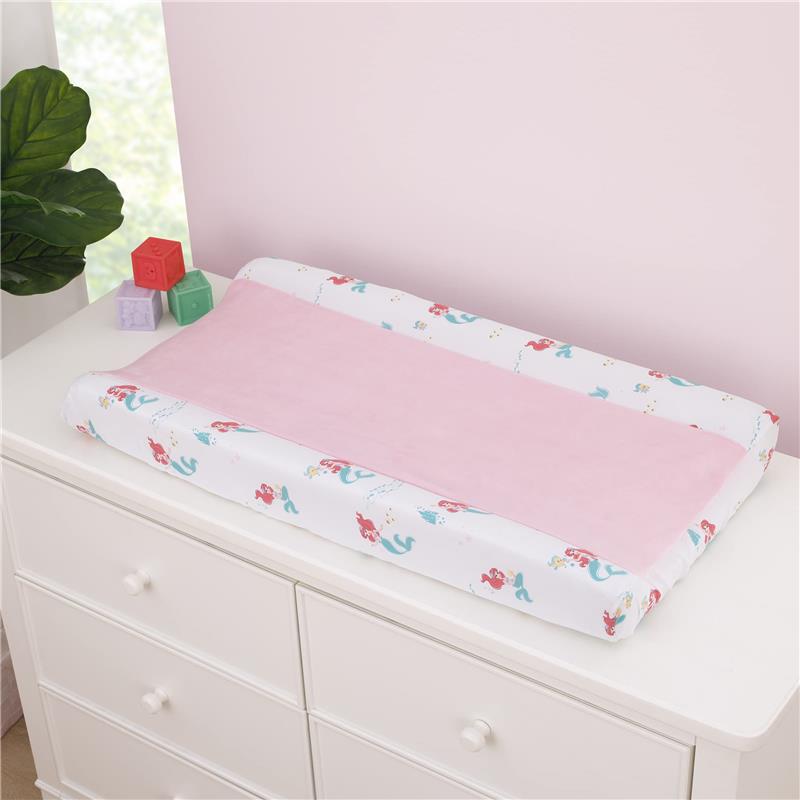 NoJo Disney Ariel Watercolor Wishes changing pad cover featuring a pink center and mermaid-themed border on a dresser.