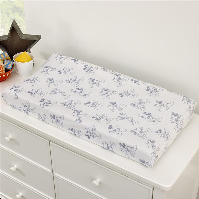 Super soft changing pad cover featuring a Mickey Mouse design in gray on a white background, placed on a dresser.