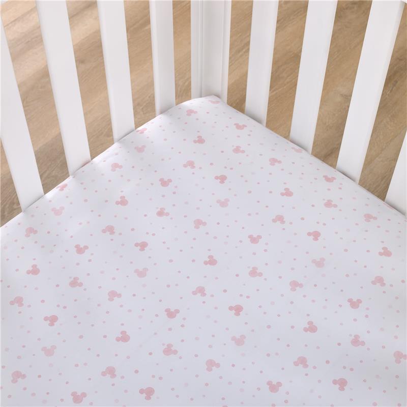 Fitted crib sheet featuring a polka dot design with Minnie Mouse icons in soft pink and white.