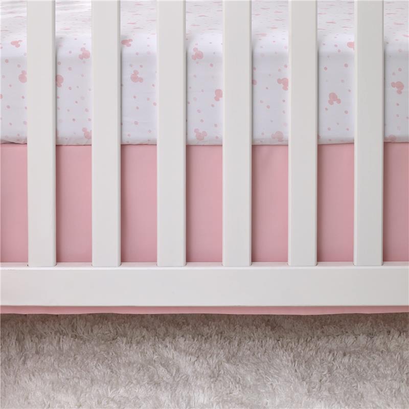 Fitted crib sheet featuring a white background with pink Minnie Mouse icons and polka dots, set on a pink crib with white slats.