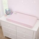 Pink changing pad cover featuring a princess design, placed on a white dresser alongside a clock and decorative items.