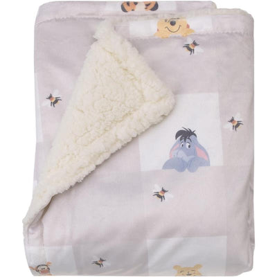 Winnie the Pooh Hugs & Honeycombs baby blanket featuring soft fleece and cute characters like Eeyore and bees on a pastel background.
