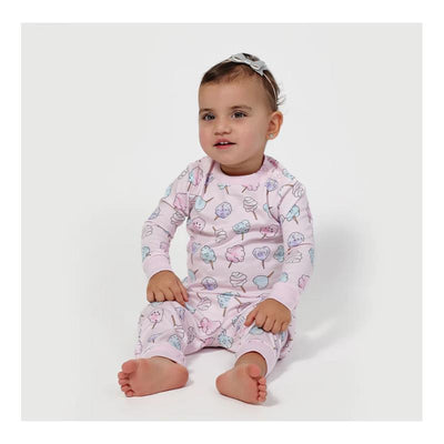 Baby girl sits with a smile, wearing a pink cotton pajama set featuring colorful cotton candy prints.
