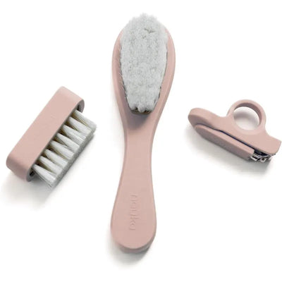 Baby grooming kit by Nouka in soft blush, including a soft brush, comb, and nail clipper.